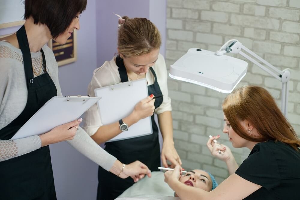 professional-cosmetology-courses-permanent-makeup-female-beautician-sketching-up-symmetrical-eyebrows
